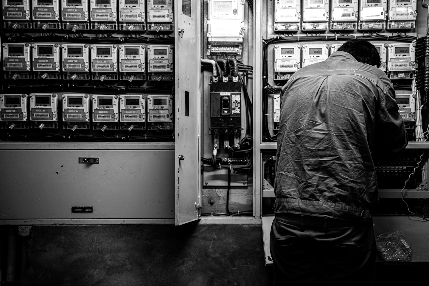 Person working on an open electrical panel with complex wiring.